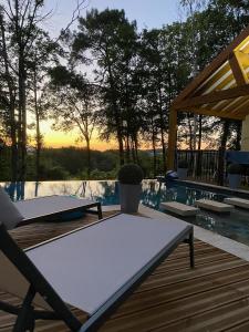 a table sitting on a deck next to a pool at Villa Nature & Douets - aux portes du Mans - 5 chambres climatisées - piscine à débordement et terrain arboré d'1 hectare in La Chapelle-Saint-Aubin