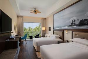 a hotel room with two beds and a large window at Sheraton Kosgoda Turtle Beach Resort in Bentota