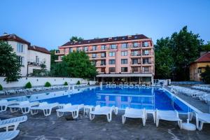 una gran piscina con sillas blancas y un edificio en SPA Hotel Medicus, en Varshets
