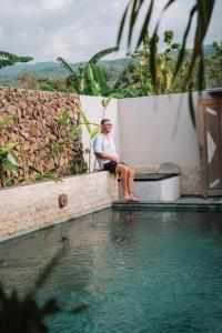 Ein Mann auf einer Bank neben einem Pool in der Unterkunft Villa Soluna Lovina in Lovina