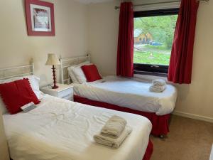 two beds in a room with red curtains and a window at Mountain Thyme Lodge in Kilfinnan