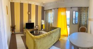 a living room with a yellow couch and a table at Janamaev in Yaoundé