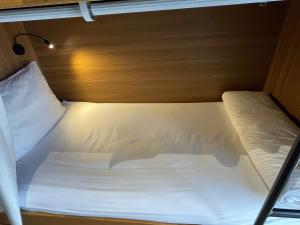 a white bed in a small room with a light at Tropical Dorm Hostel Da Nang by Haviland in Danang +10 photos