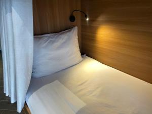 a bed with a white pillow and a light on it at Tropical Dorm Hostel Da Nang by Haviland in Danang