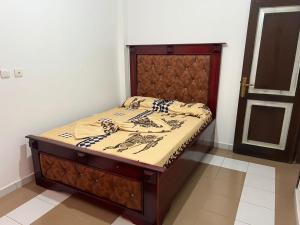 a bed in a room with a wooden headboard at Janamaev in Yaoundé