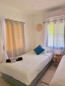 a bedroom with a bed with white sheets and blue pillows at Villa l'Aurora in Amphoe Koh Samui