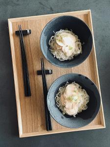 twee kommen met eten met noedels en eetstokjes op een houten dienblad bij 2R Yakushima in Yakushima