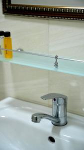 a bathroom sink with a faucet and a mirror at Astoria Inn in Toshkent-Passajir Bekati