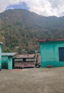 un edificio azul con una montaña en el fondo en lake & woods-a boutique lakeview property, en Bhimtal