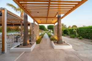 a patio with three palm trees and a wooden pergola at Cirillo Family Hotel-Christinas Studios in Mastichari