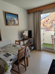 a bedroom with a bed and a television and a balcony at véritable 2 pièces, vue panoramique in Allos