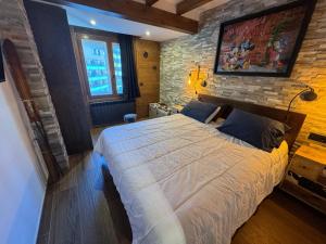 a bedroom with a large bed with a brick wall at Immodelpas Pic Blanc in Pas de la Casa