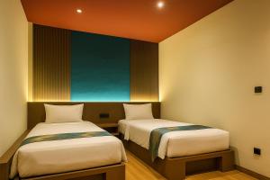 two beds in a small room with a painting on the wall at Jazotel Batam in Jodoh