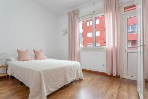 a white bedroom with a bed and a window at Piso en pleno centro in Santa Cruz de Tenerife