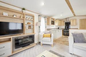 Una sala de estar con un televisor grande y una cocina. en Squirrel Lodge with Hot Tub, en Pocklington