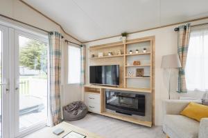 Una sala de estar con televisión y chimenea. en Squirrel Lodge with Hot Tub, en Pocklington