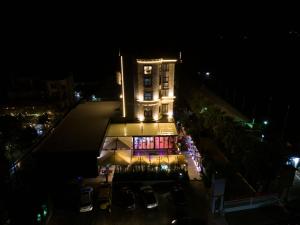 un edificio iluminado por la noche con coches aparcados fuera en Si'Hana Hotel, en Elbasan