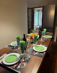 a wooden table with green plates and wine glasses at Il Palazzaccio - Tuscan Historical Villa in Reggello in Reggello