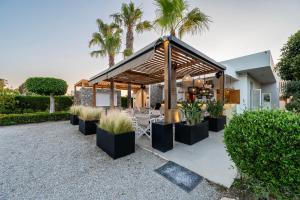 a pavilion with a table and chairs and palm trees at Cirillo Family Hotel-Christinas Studios in Mastichari