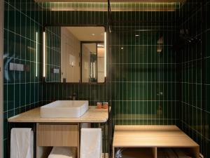 ein grün gefliestes Bad mit einem Waschbecken und einem Spiegel in der Unterkunft Orange Hotel Shanghai New International Expo Centre in Shanghai + 22 Fotos
