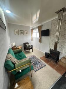 a living room with a green couch and a fireplace at The Stables & Silos in Braintree