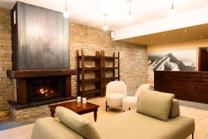 a living room with a fireplace and a couch and chairs at Hotel Chalet Seggiovia in Pontechianale