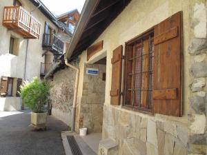 un bâtiment avec des portes en bois et une usine de pot dans une rue dans l'établissement Chalet 11 pers, 5 ch, pied des pistes, balcon, parking, Wi-Fi, cheminée, Serre Chevalier - FR-1-762-27, à Saint-Chaffrey