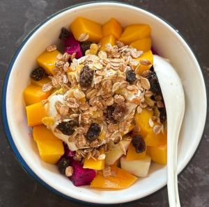 a bowl of fruit and nuts with a spoon at Khao Sok Hill Top Resort in Khao Sok National Park