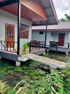 a house with a koi pond in front of it at ปารมีฟาร์มสเตย์ in Ban Chao Nam