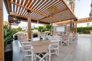 a restaurant with tables and chairs under a wooden pergola at Cirillo Family Hotel-Christinas Studios in Mastichari