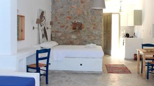 a bedroom with a white bed and a stone wall at Dimitra Studios in Aegiali +14 photos