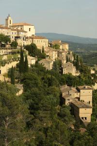 a group of buildings on a hill with trees at La petite Maison de Gordes in Gordes