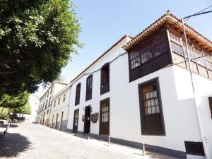 a white building with wooden windows on a street at Ziggy's Mountain Retreat in Vilaflor