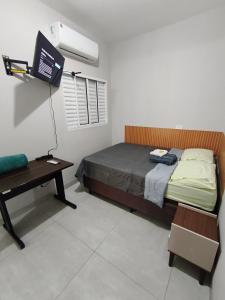 a bedroom with a bed and a desk and a television at Residencial Yama - Hospedagens in Paranavaí