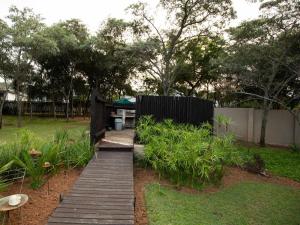 a wooden walkway in a garden with a fence at Weavers Nest Guesthouse in Modimolle