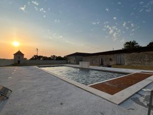 a swimming pool with a sunset in the background at Logis Poussard in Arthenac