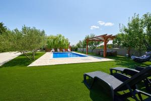 um quintal com piscina com cadeiras e um gazebo em Family-friendly apartments with swimming pool Ljubac, Zadar - 14148 em Krneša