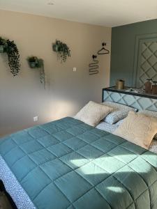 un letto blu in una camera da letto con piante sul muro di Le Hangar - Studio esprit industriel a Pont-Rémy