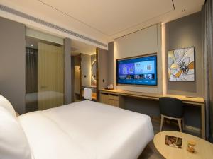 ein Hotelzimmer mit einem Bett und einem Flachbildfernseher in der Unterkunft Orange Hotel Shanghai New International Expo Centre in Shanghai