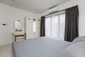a white bedroom with a large bed and a window at Ali Cozy Houses in Ban Thalat Choeng Thale