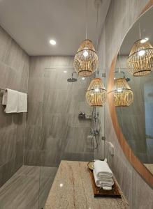 a bathroom with a shower with a mirror and chandeliers at la la lay beach house in Tab Kaek Beach