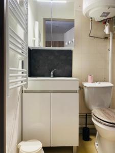 a white bathroom with a sink and a toilet at Le petit soleil in Lamalou-les-Bains