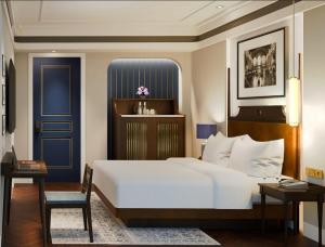 ein Schlafzimmer mit einem weißen Bett und einer blauen Tür in der Unterkunft Ashley NewAir Menteng with Air Purifier in Jakarta