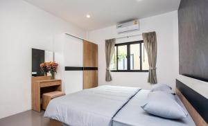 a white bedroom with a bed and a window at Ali Cozy Houses in Ban Thalat Choeng Thale