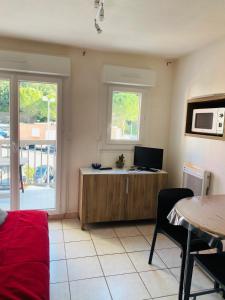 a living room with a desk with a computer and a table at Le petit soleil in Lamalou-les-Bains