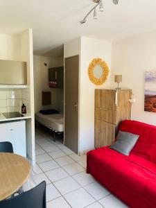a living room with a red couch and a kitchen at Le petit soleil in Lamalou-les-Bains