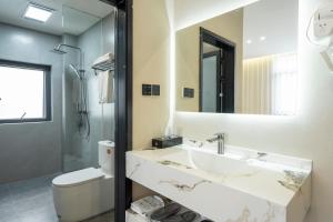 a bathroom with a sink and a toilet and a mirror at Yu Ni Meisu-wang xian gu Branch in Qiaotou +40 photos