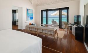 una camera con letto e un soggiorno con TV di Noku Maldives, Vignette Collection a Kuredu