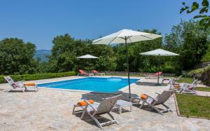 einen Pool mit Stühlen und Sonnenschirmen neben einem Pool in der Unterkunft Family friendly house with a swimming pool Katun Boljunski, Central Istria - Sredisnja Istra - 15627 in Boljun