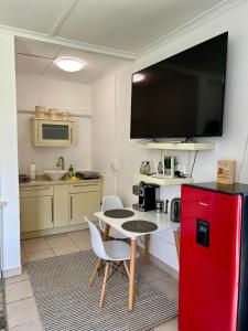 eine Küche mit einem roten Kühlschrank sowie einem Tisch und Stühlen in der Unterkunft Cozy Cottage in idyllic greenery in Harkerville